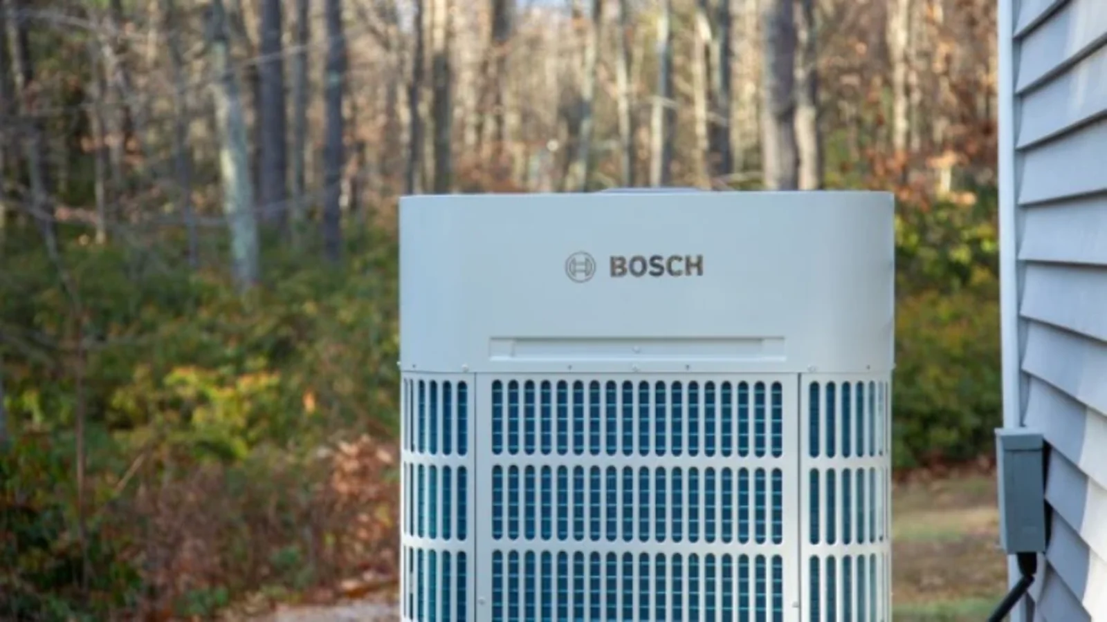 Bosch outdoor heat-pump unit installed beside a wooded home