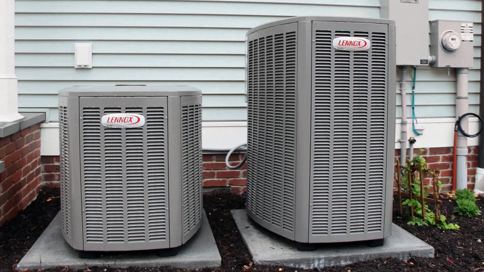 Two Lennox outdoor HVAC units installed beside a home