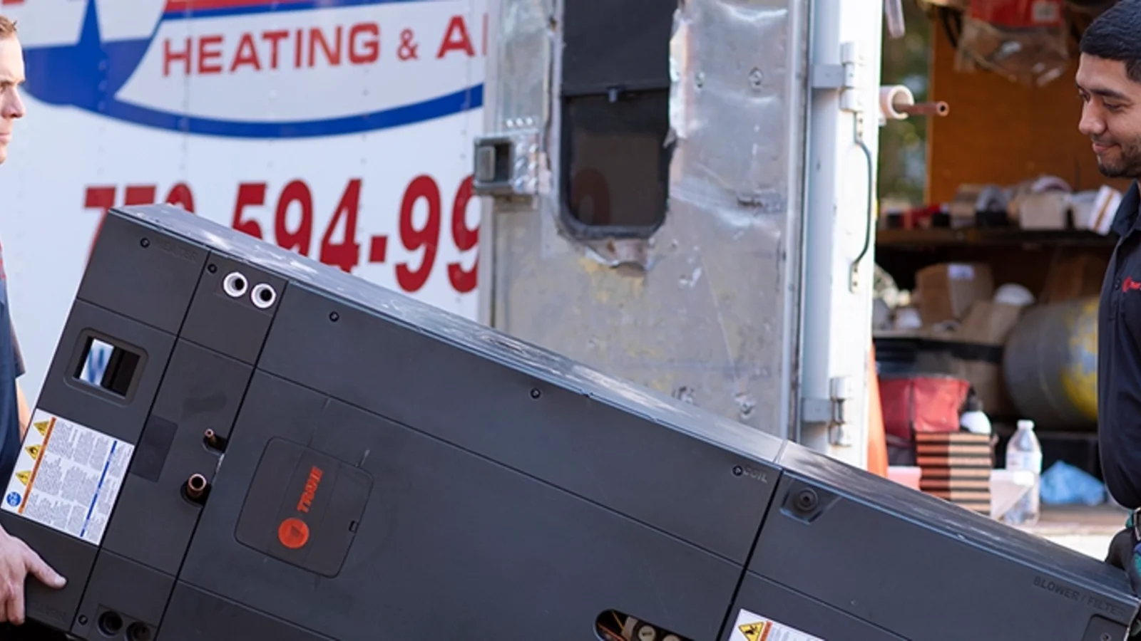 HVAC installers carrying Trane equipment during an installation
