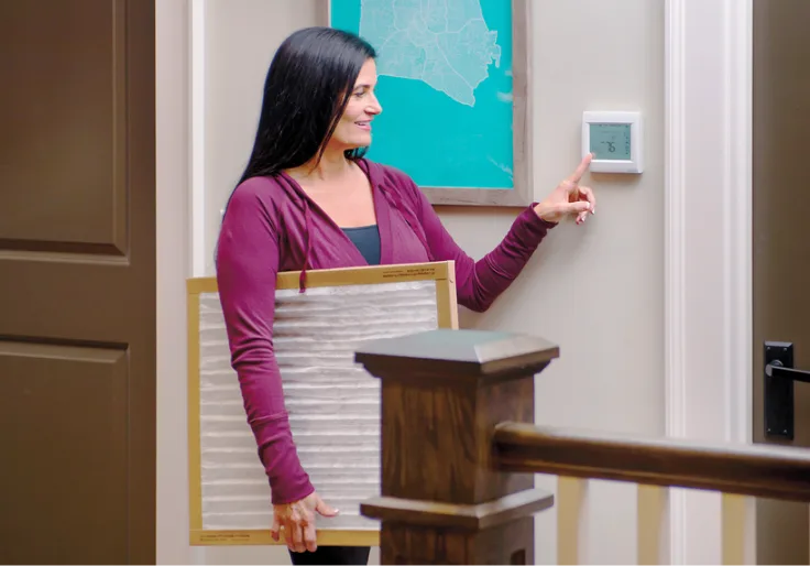 Homeowner adjusting an Amana HVAC thermostat
