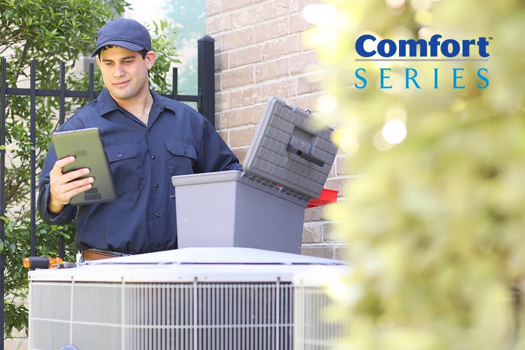 Technician servicing a Carrier Comfort series air conditioner