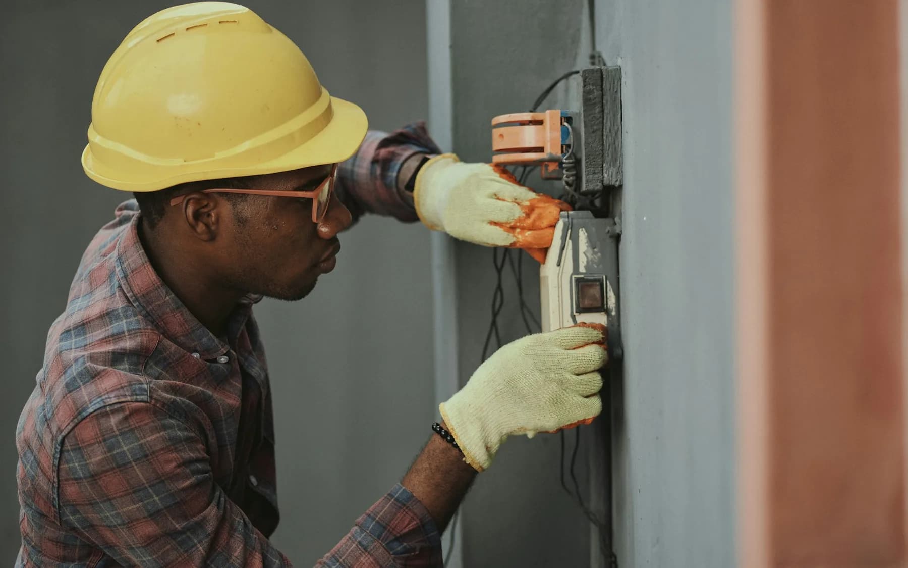 Electrician testing wiring connections while wearing protective equipment