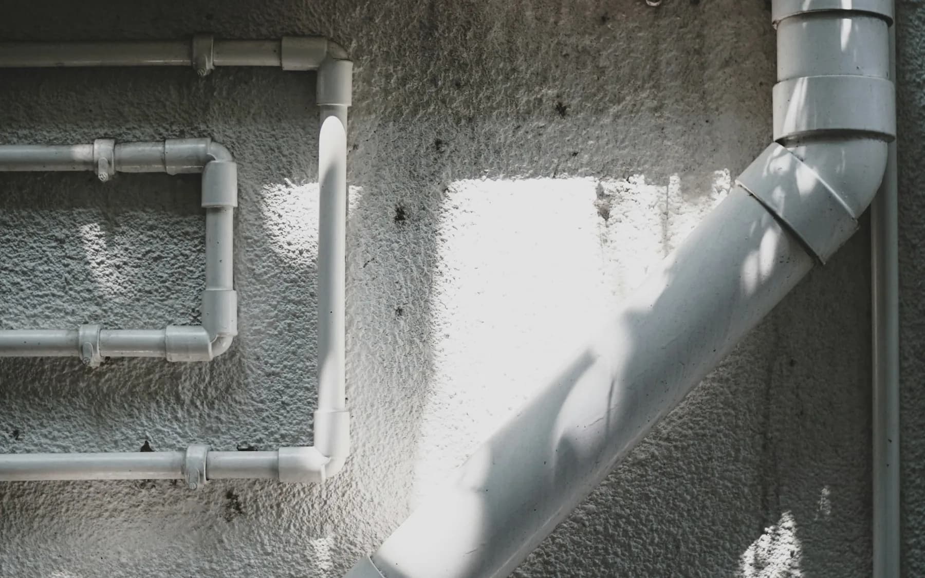 White condensate-style drain pipes routed along an exterior wall