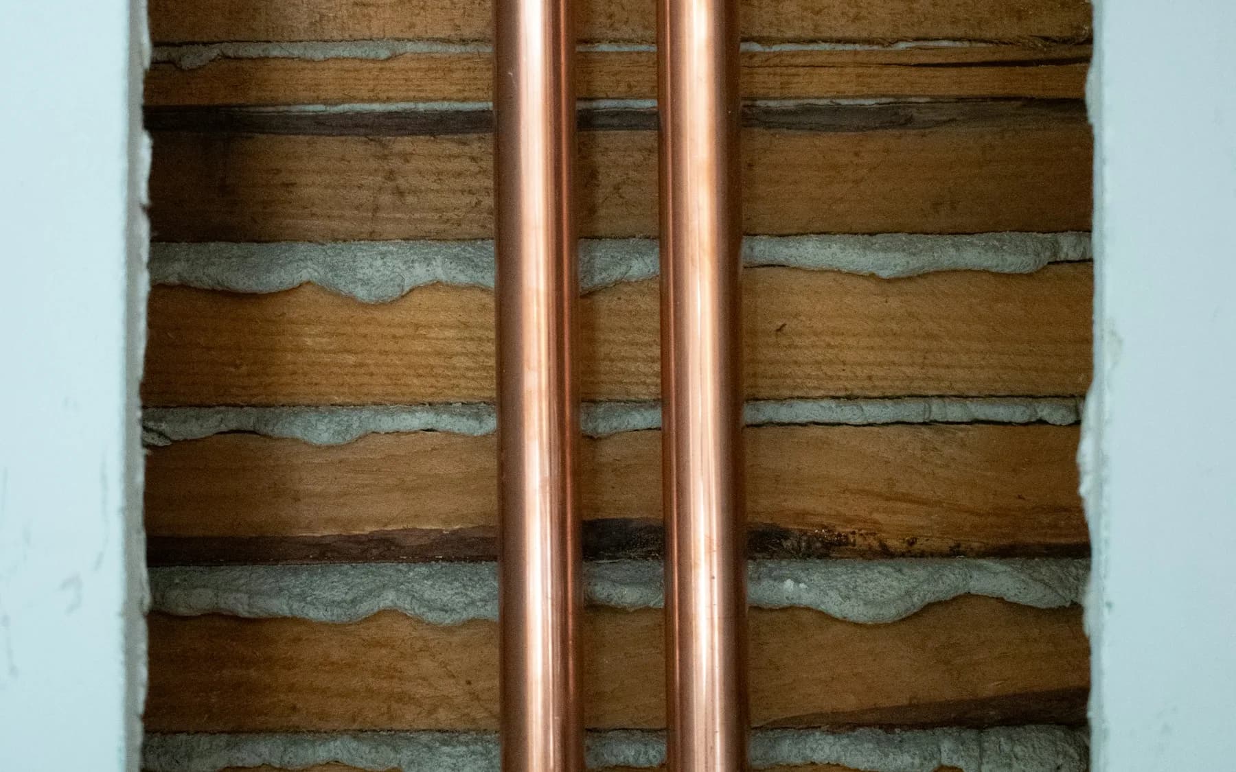 Two copper refrigerant lines installed vertically against a wall