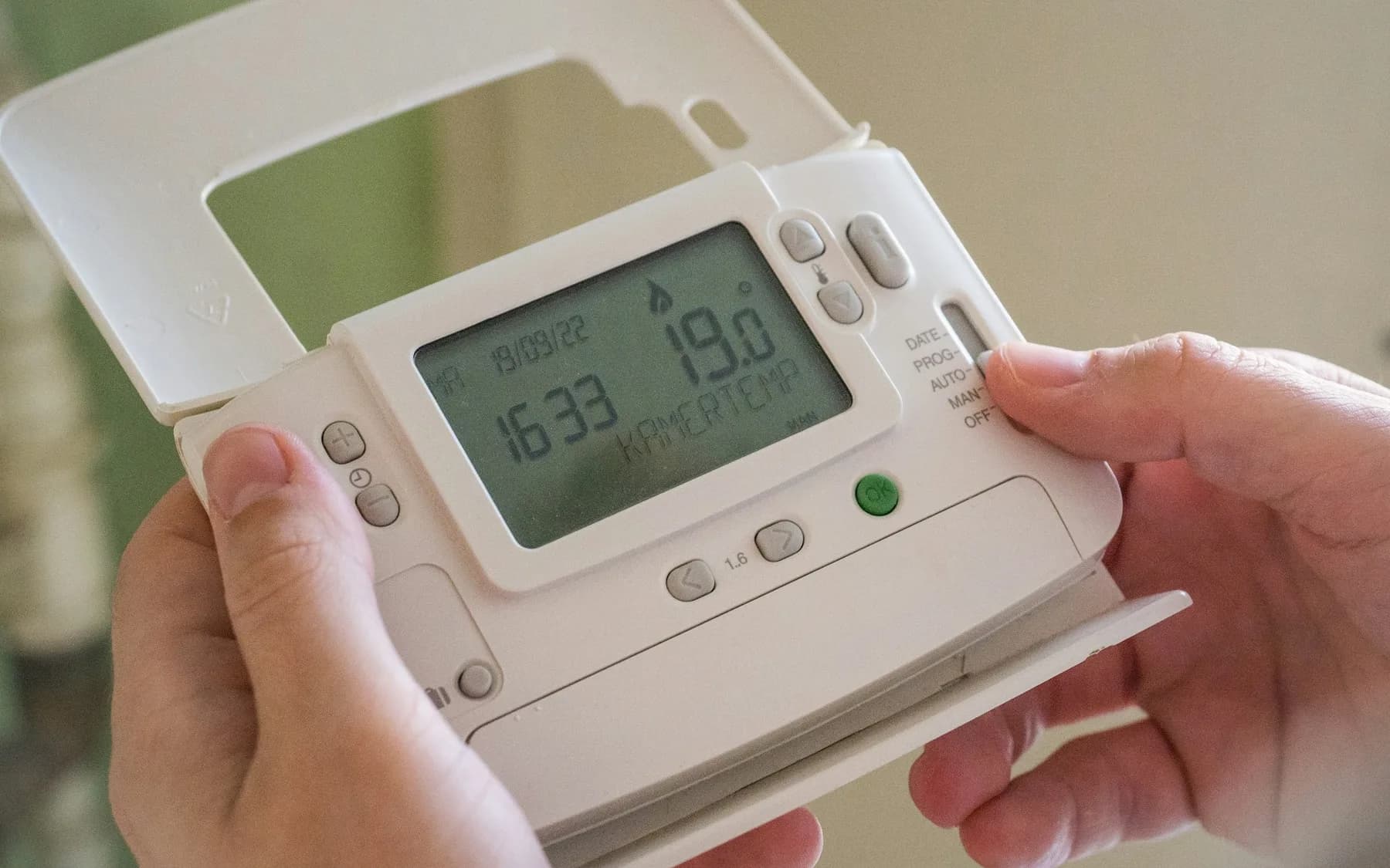 Person holding a digital home energy control device in both hands