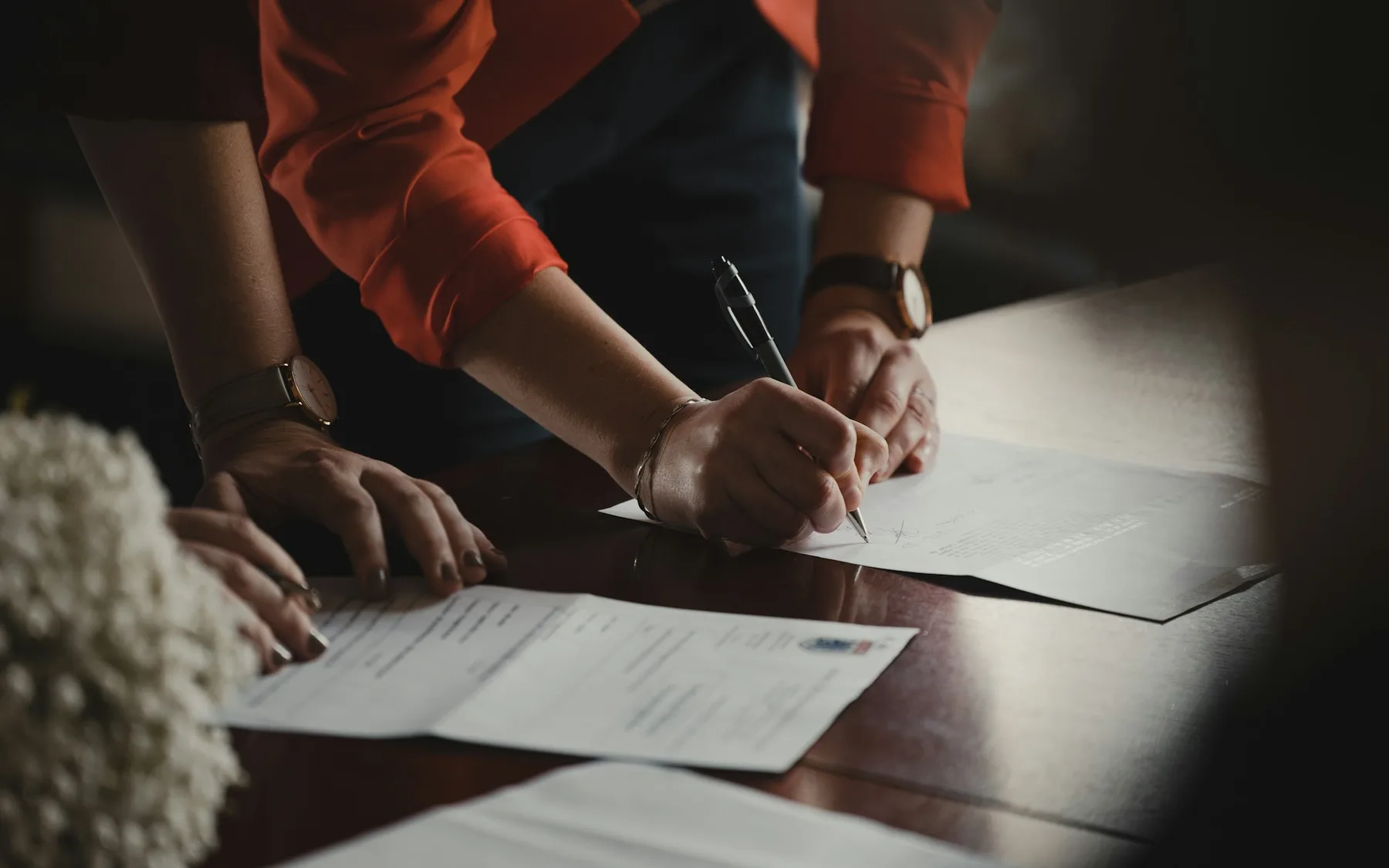 Person reviewing and writing notes on project paperwork at a table