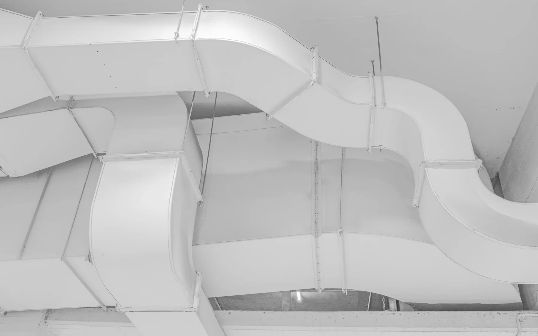 Large white ventilation ducts routed across an interior ceiling