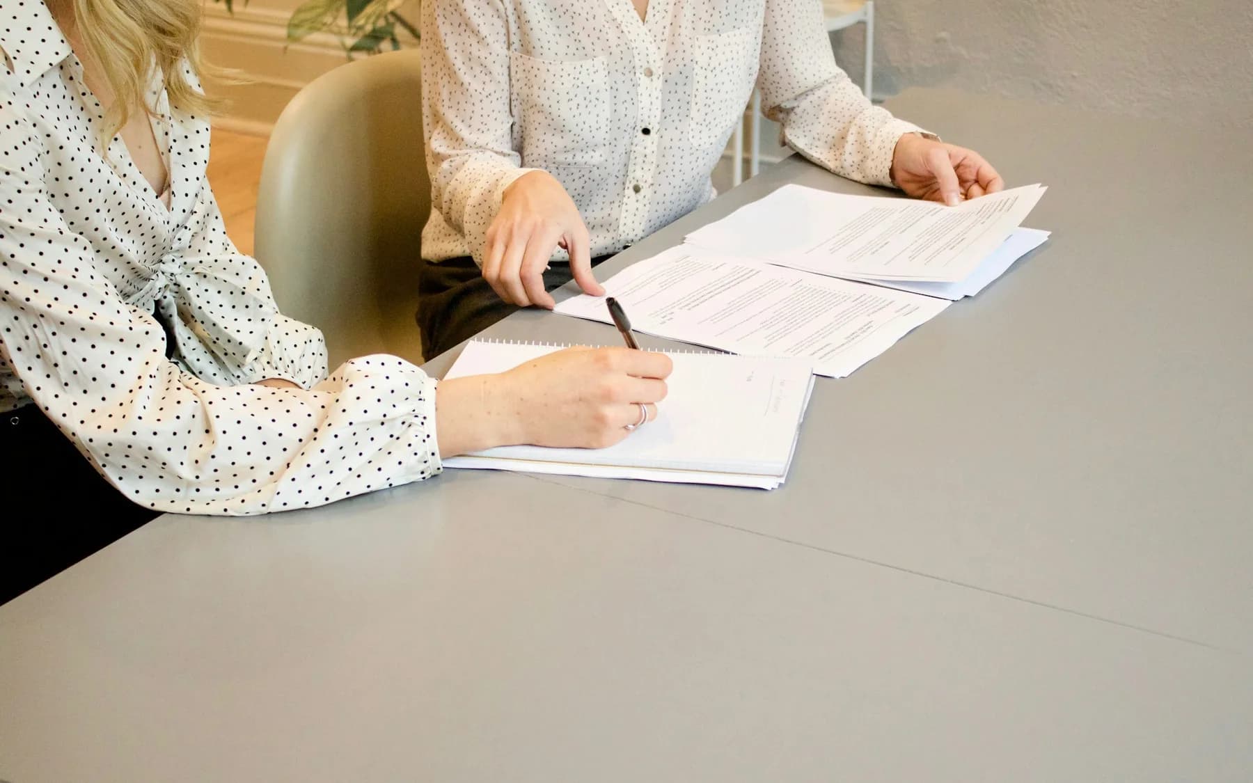 Two people reviewing and signing detailed proposal documents together