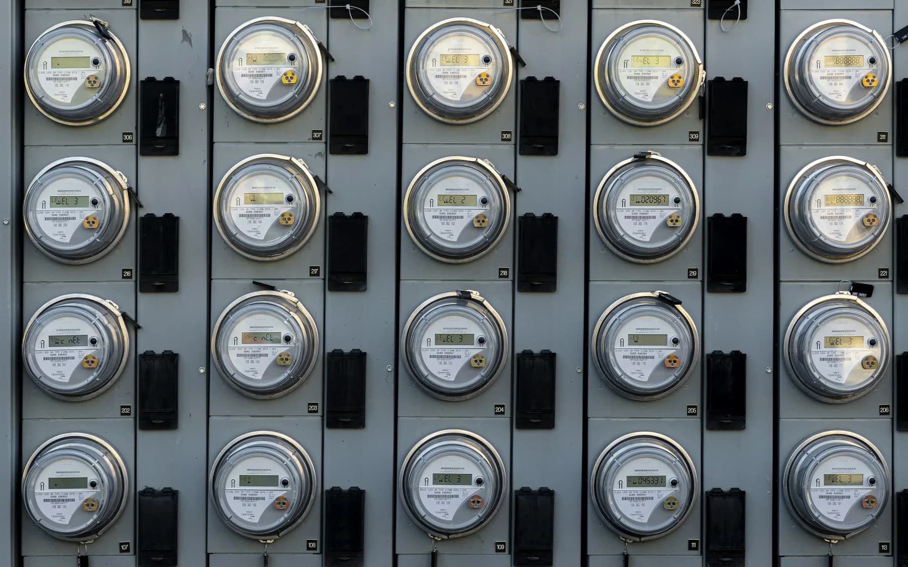 Rows of residential-style electricity meters mounted on a utility panel