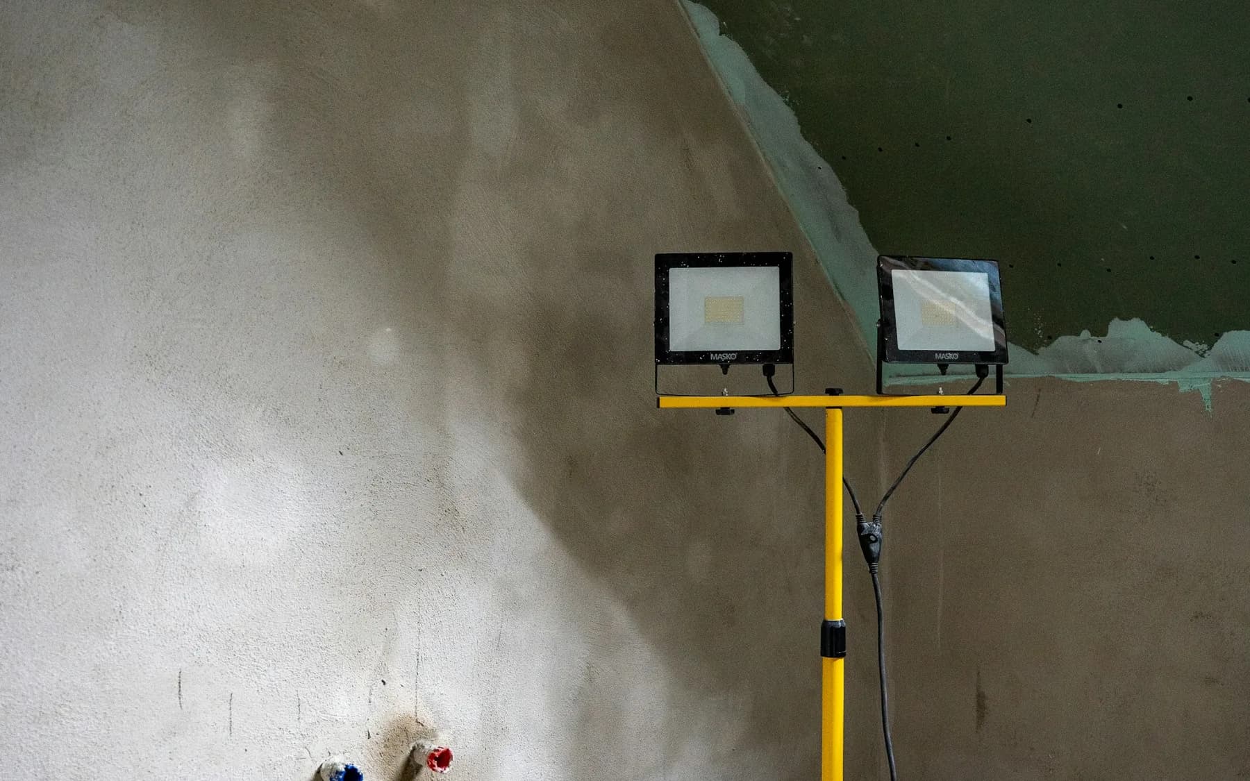 Unfinished room with new plaster and work lighting during construction